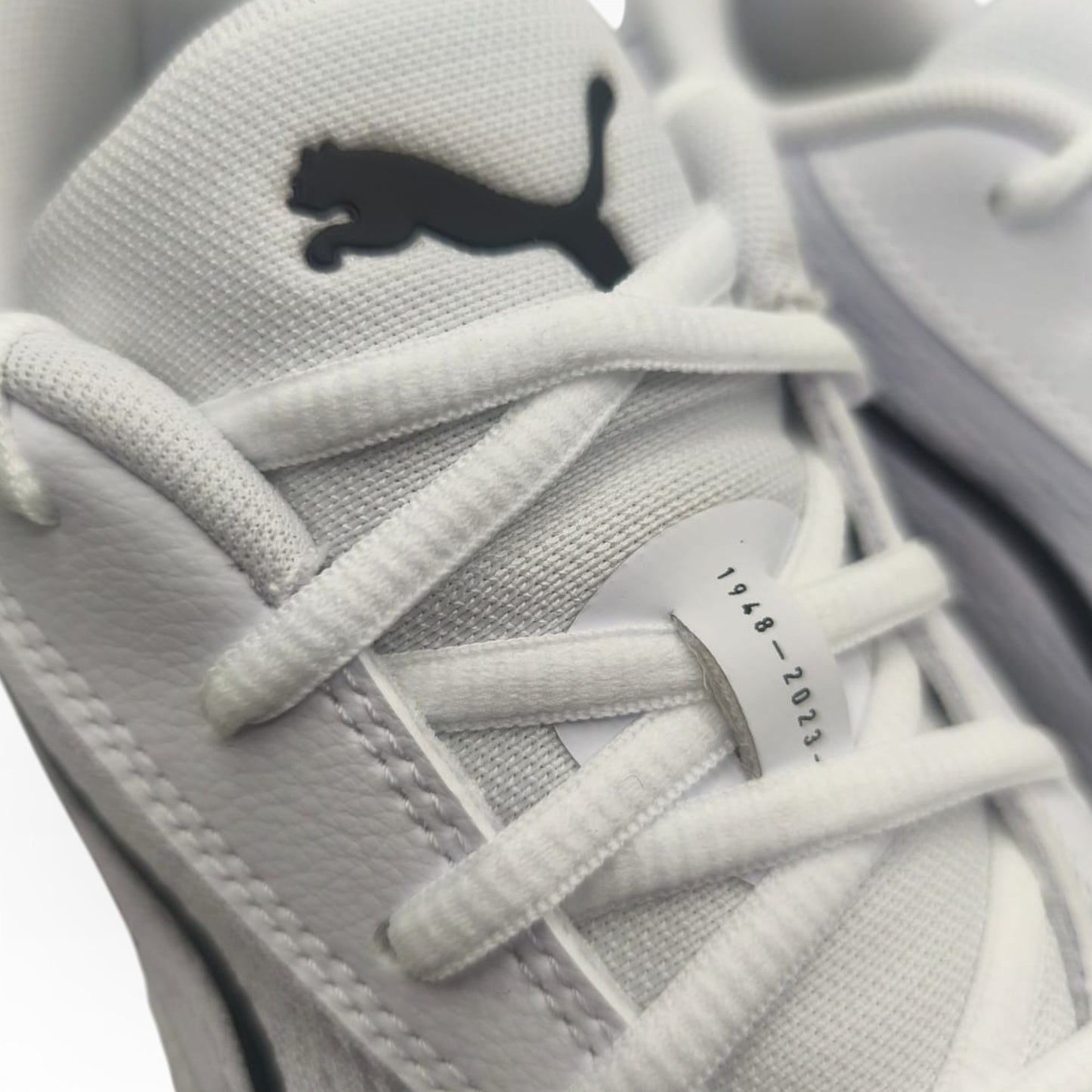 Gros plan sur baskets Puma blanches, logo noir visible, boutique LA CHAUSSURERIE