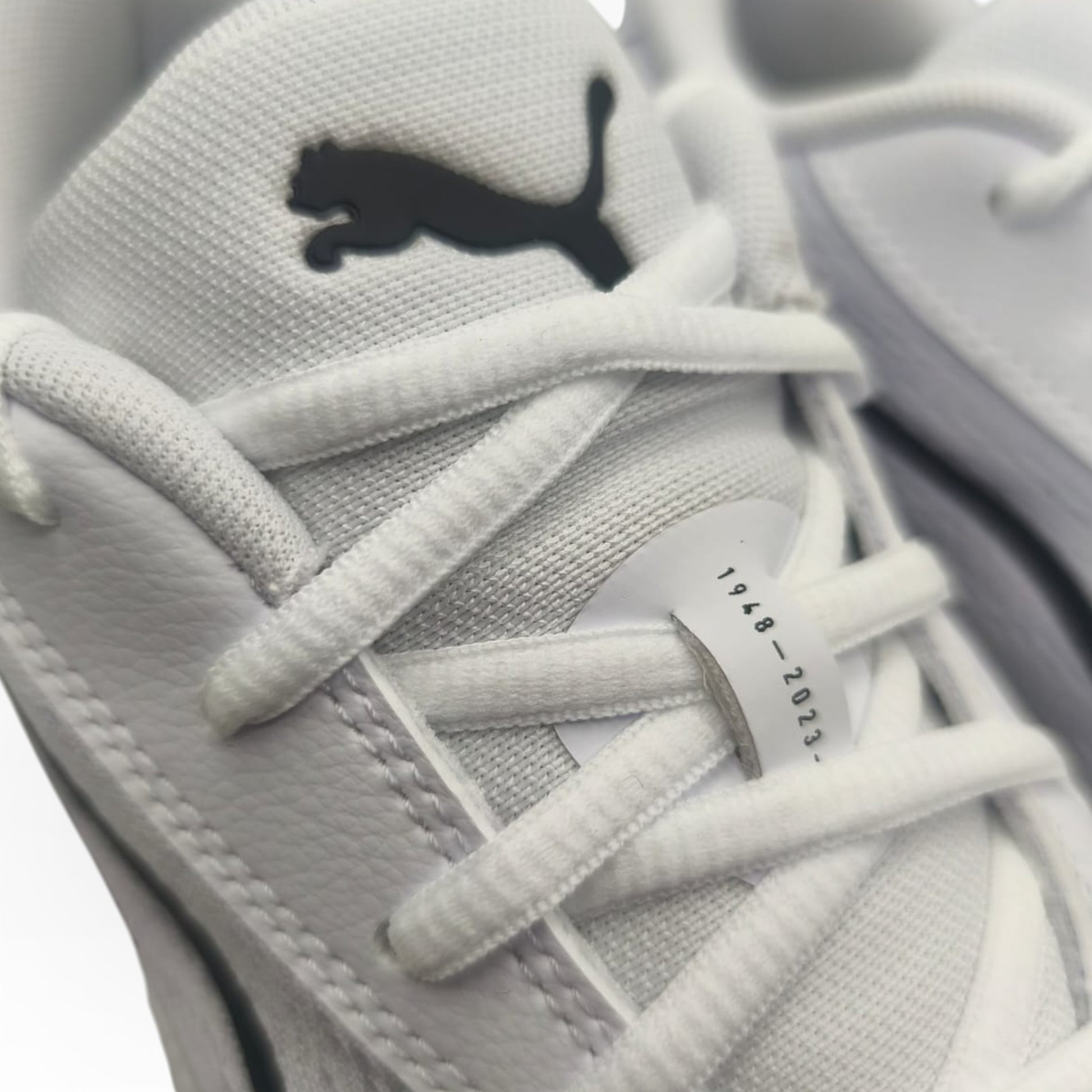 Gros plan sur baskets Puma blanches, logo noir visible, boutique LA CHAUSSURERIE