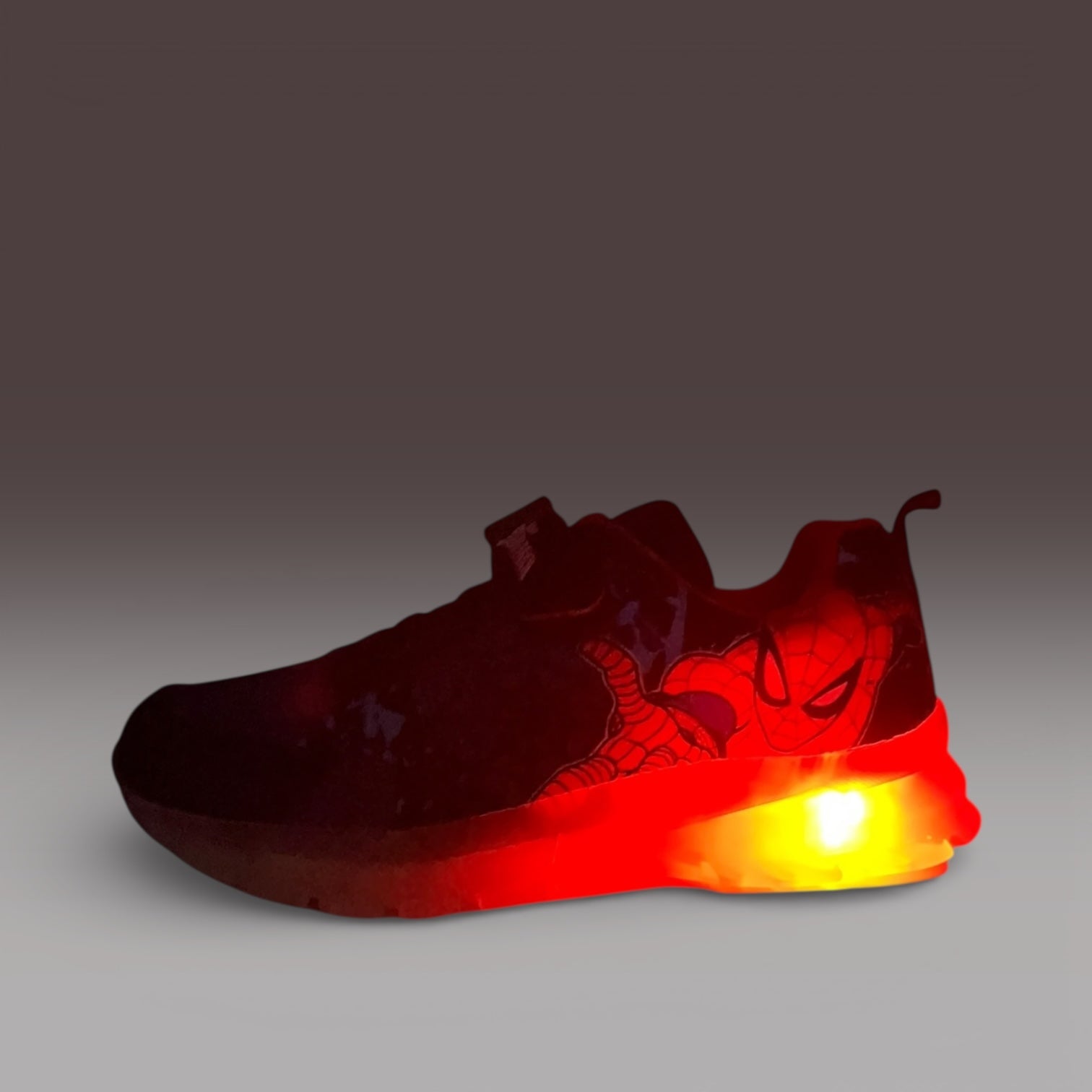 Baskets enfant Spiderman LA CHAUSSURERIE avec semelle lumineuse rouge-orange sur fond dégradé.