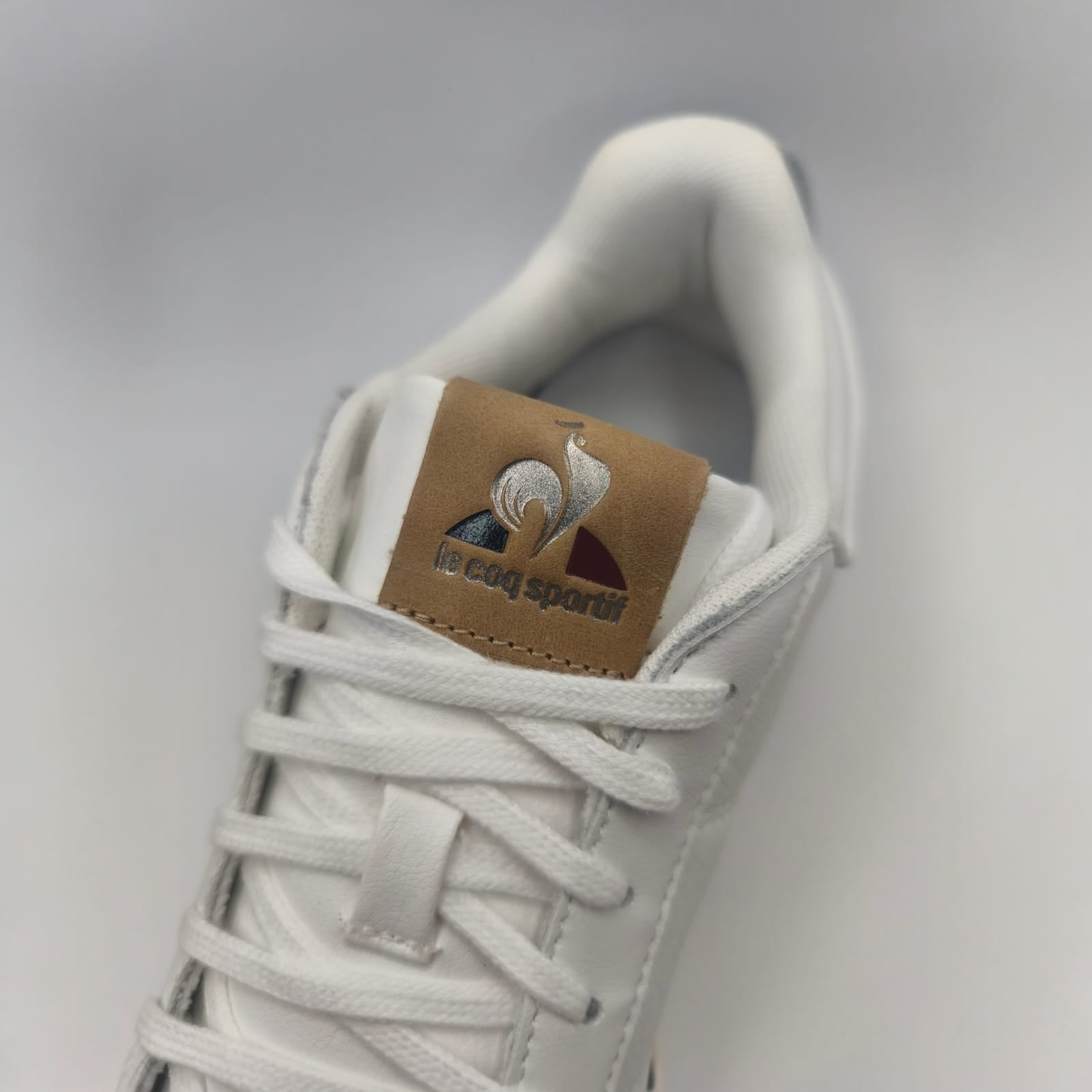 Sneaker blanche Le Coq Sportif en gros plan, lacets et logo visibles, LA CHAUSSURERIE