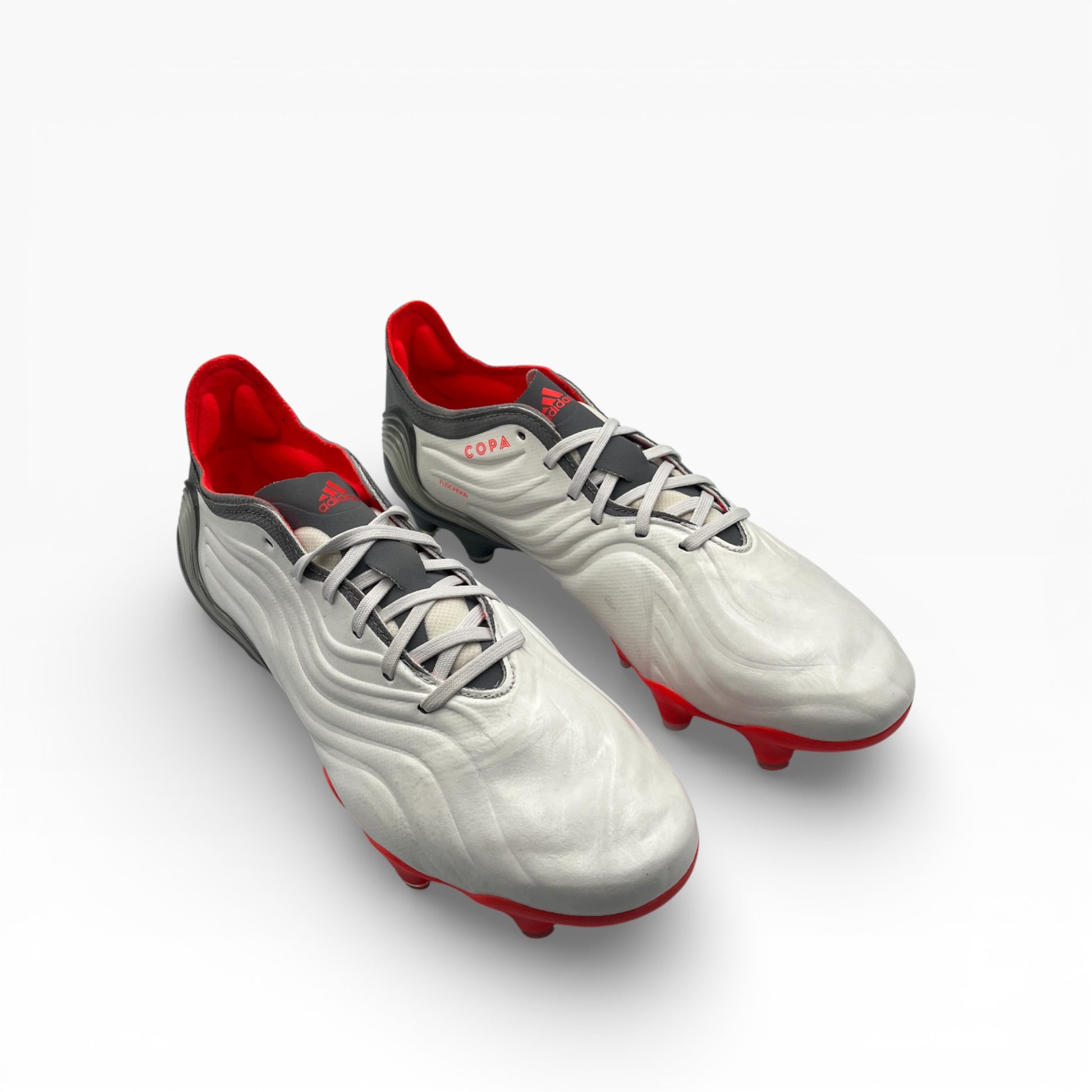 Paire de chaussures de foot Adidas Copa Sense blanches et rouges sur fond blanc, LA CHAUSSURERIE